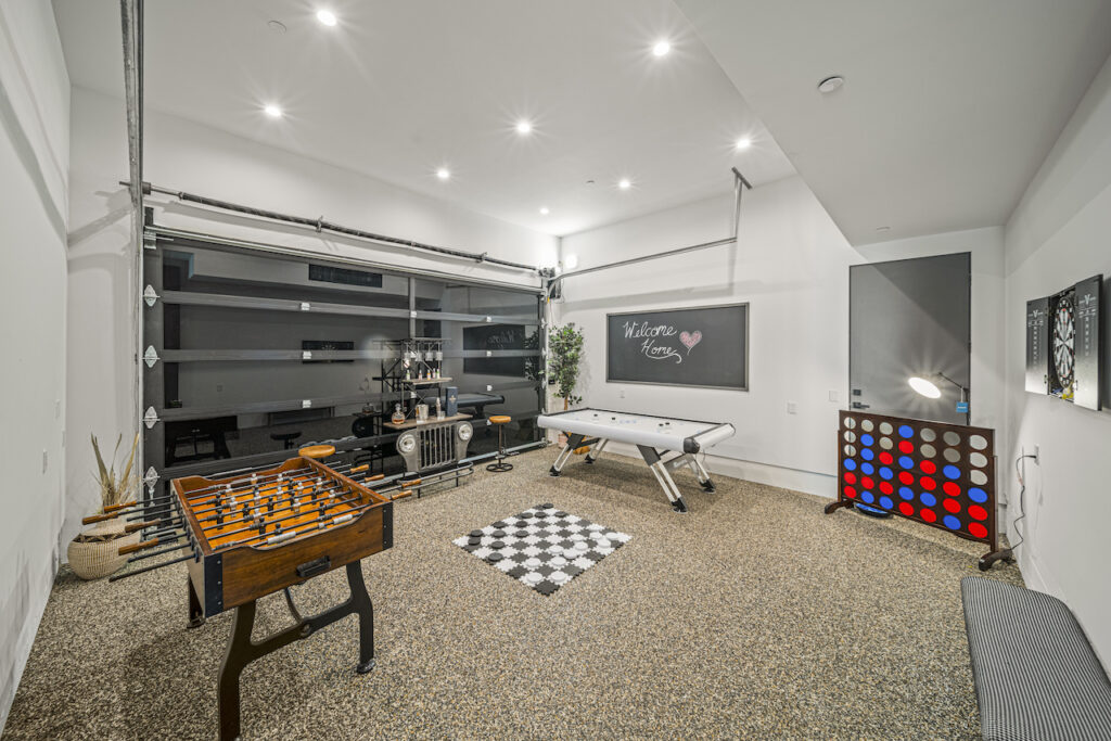 Modern garage game room with foosball and air hockey tables.