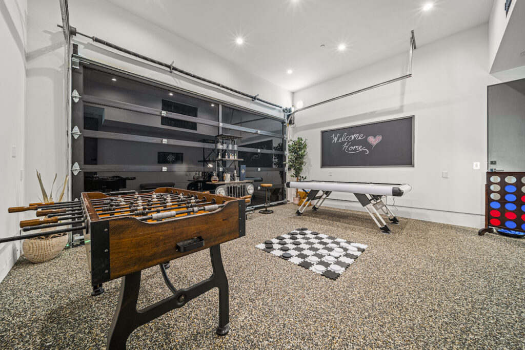 Modern garage game room with foosball and air hockey tables.