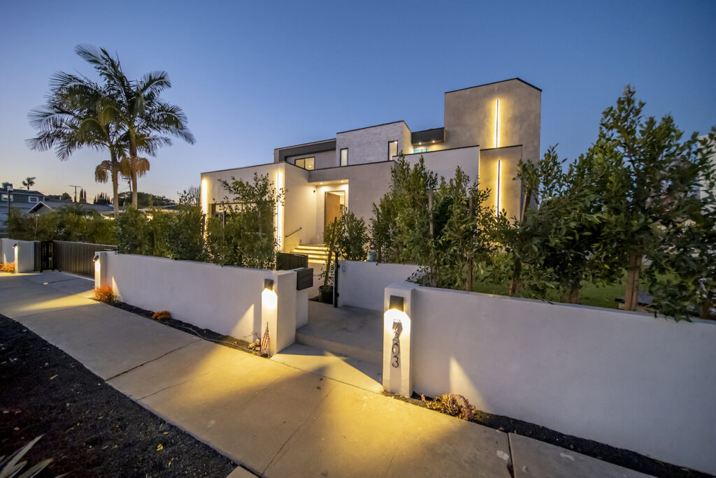 Modern home exterior at dusk with lighting.