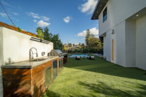 Outdoor kitchen and pool in modern backyard setting.
