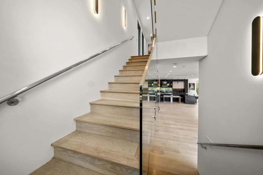 Modern interior staircase with glass railing and LED lights.