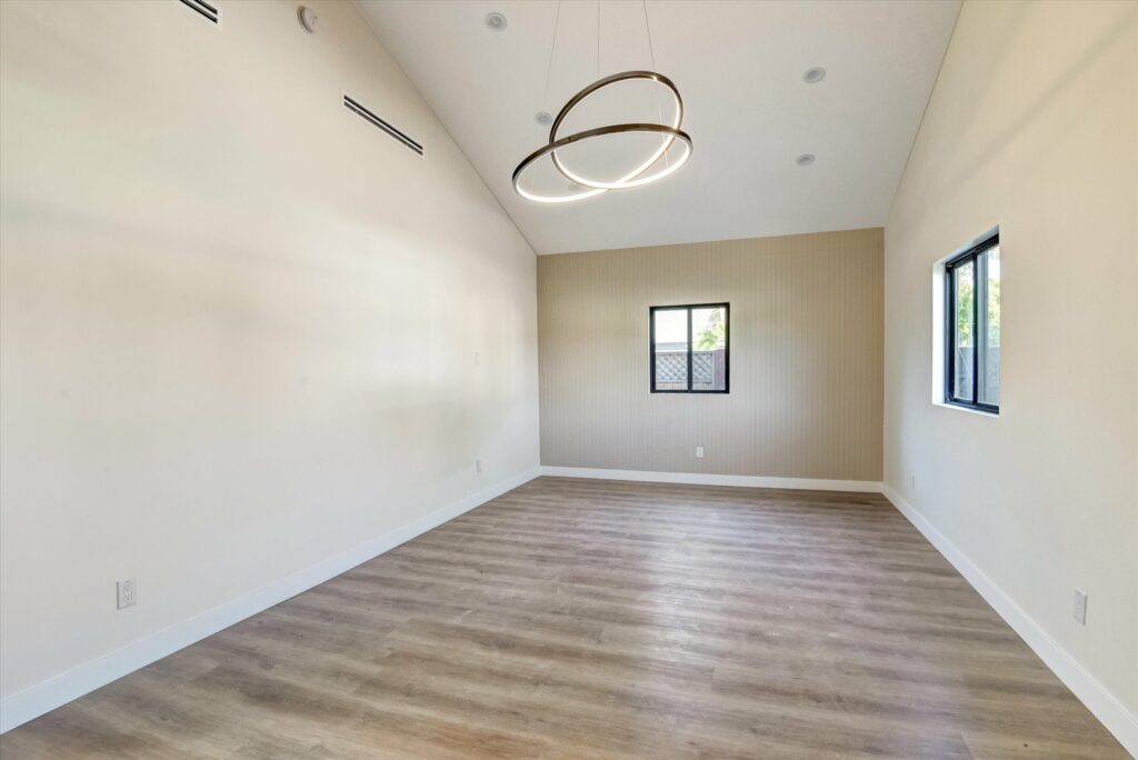 Empty room with modern lighting and wood floor.