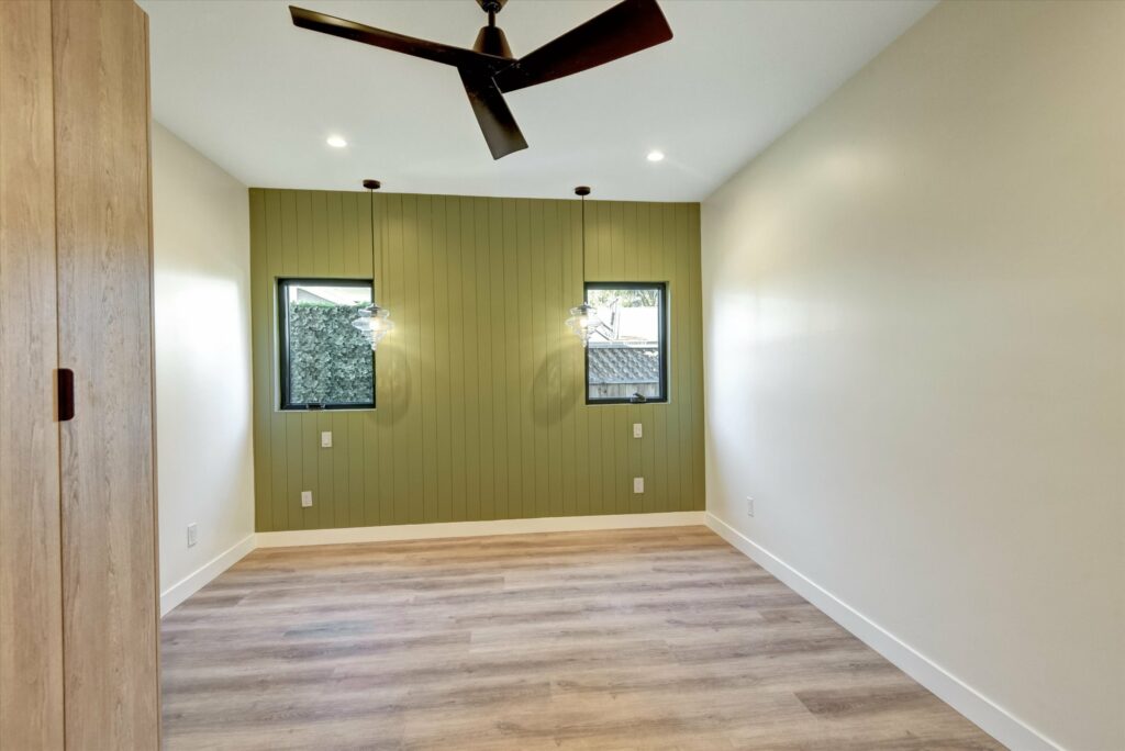 Modern empty room with hardwood floors and green accent wall.