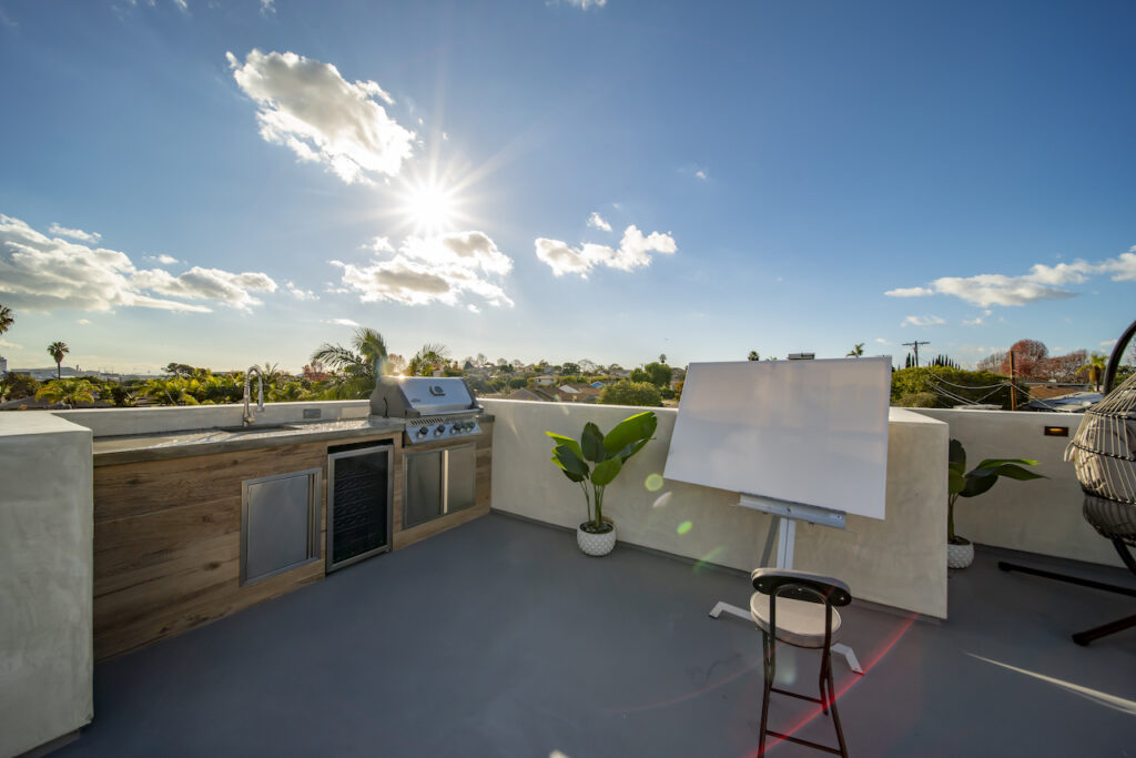 Sunny rooftop terrace with outdoor kitchen and easel.