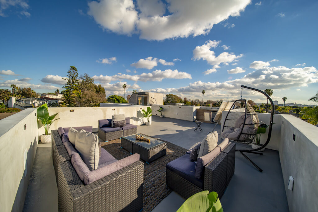 Rooftop patio furniture under blue sky with clouds.