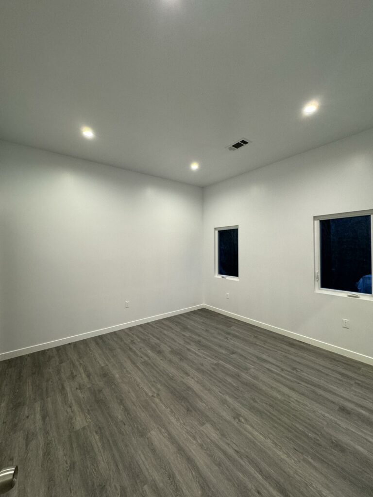 Empty room with gray flooring and ceiling lights.