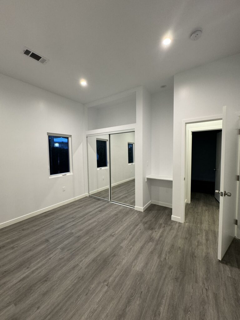 Empty room with gray flooring and mirrored closet door.
