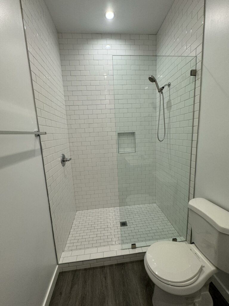 Modern white tiled bathroom with walk-in shower.