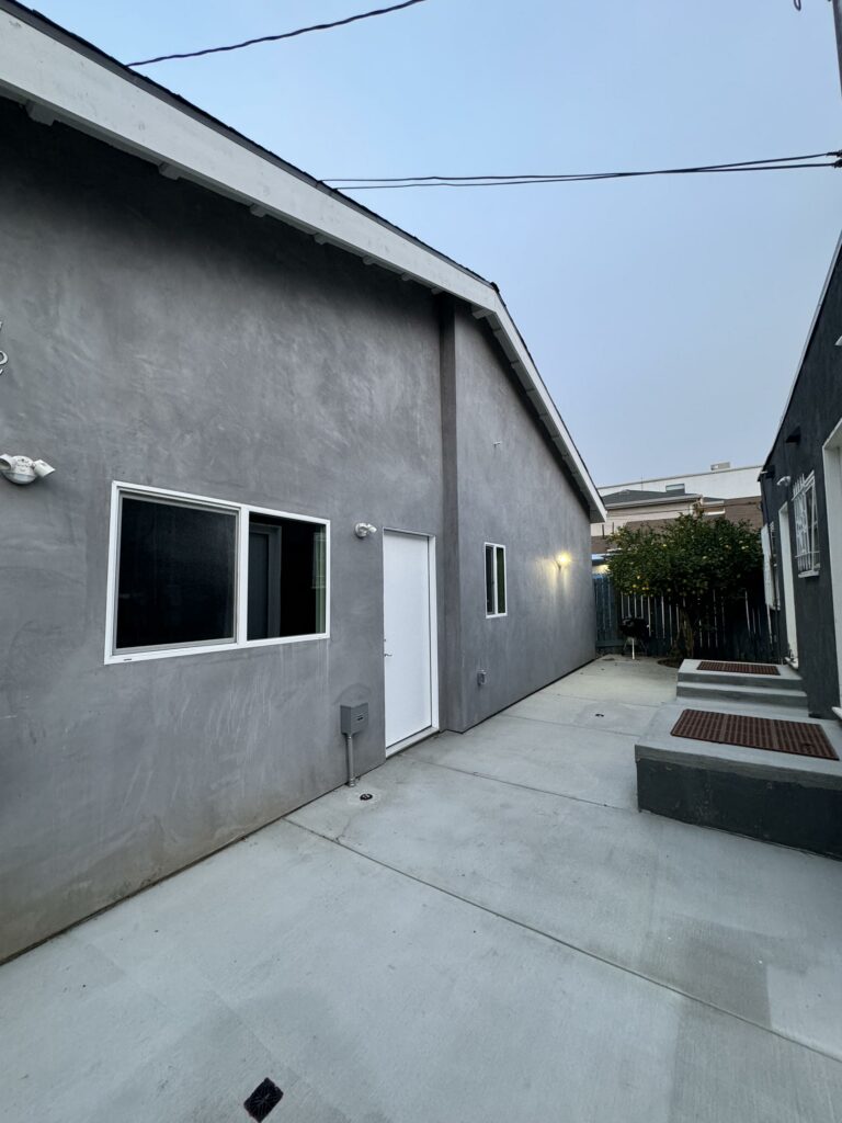 Gray building alleyway with concrete ground at dusk.