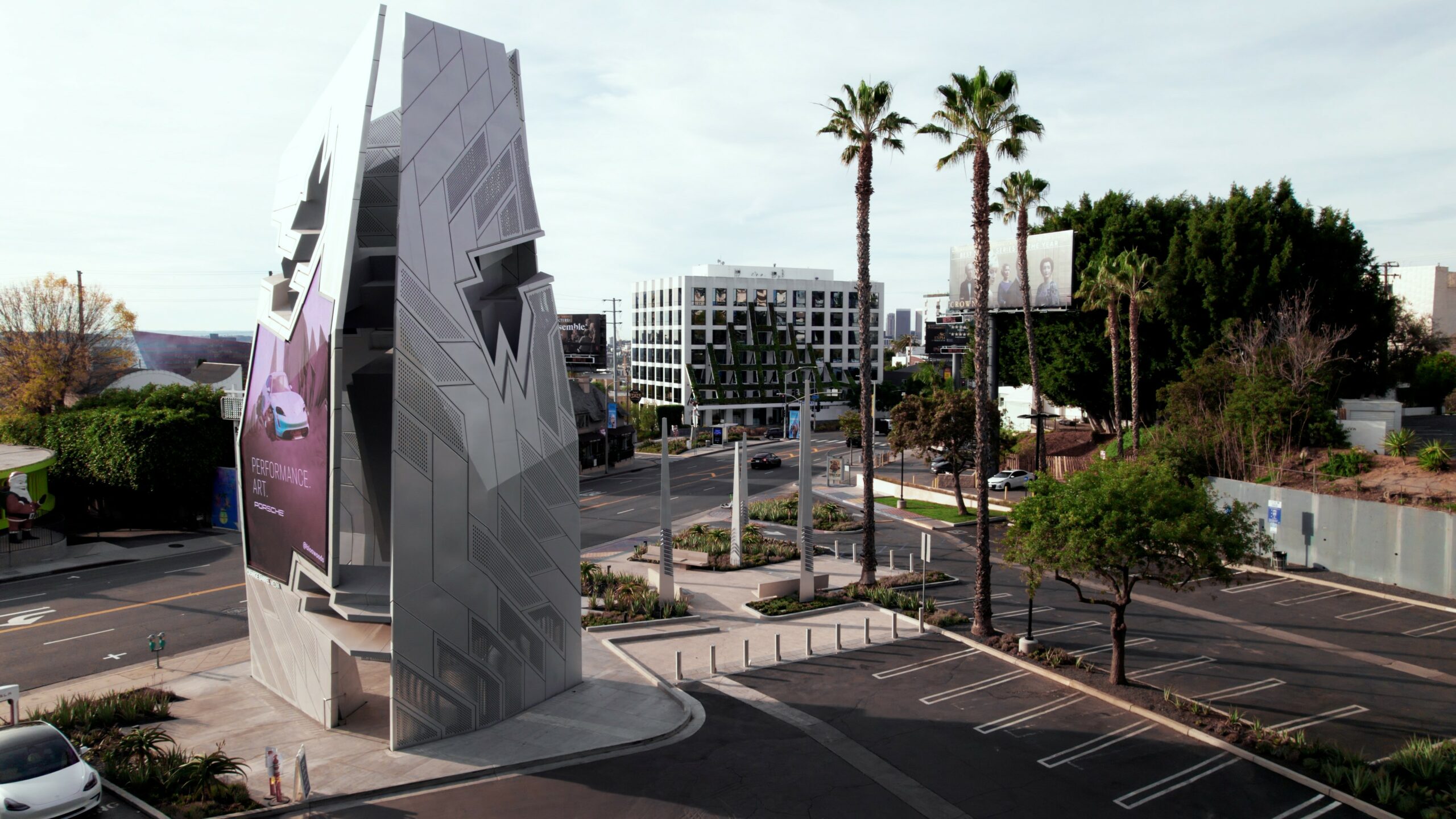 Futuristic building facade with palm trees and parked cars.