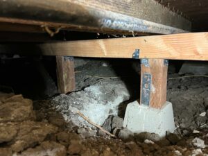 Crawlspace with new wooden support beams and concrete footing.