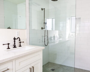 Modern white tiled bathroom with shower and vanity.