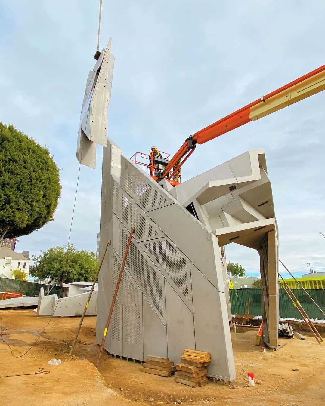 Construction workers assemble large structure with crane.