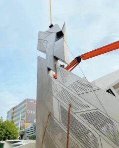 Construction worker installing metal structure with crane.