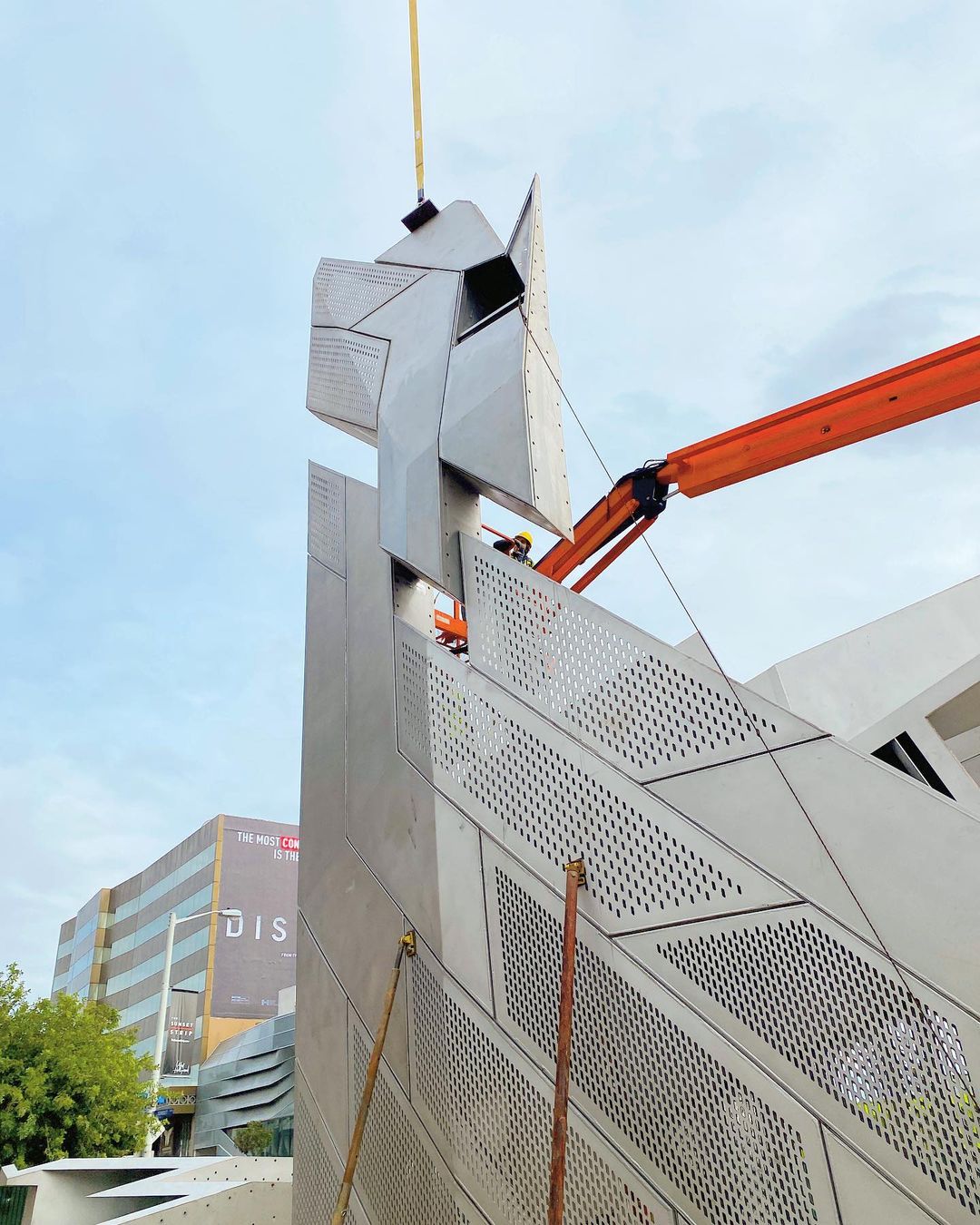 Construction worker installing metal structure with crane.