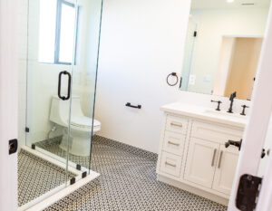 Modern bathroom with glass shower and patterned floor tiles.