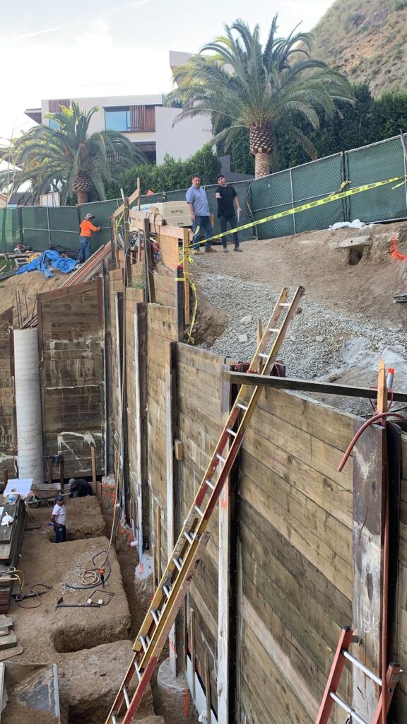 Workers at residential construction site with retaining walls.