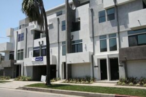 Modern apartment complex with palm tree.