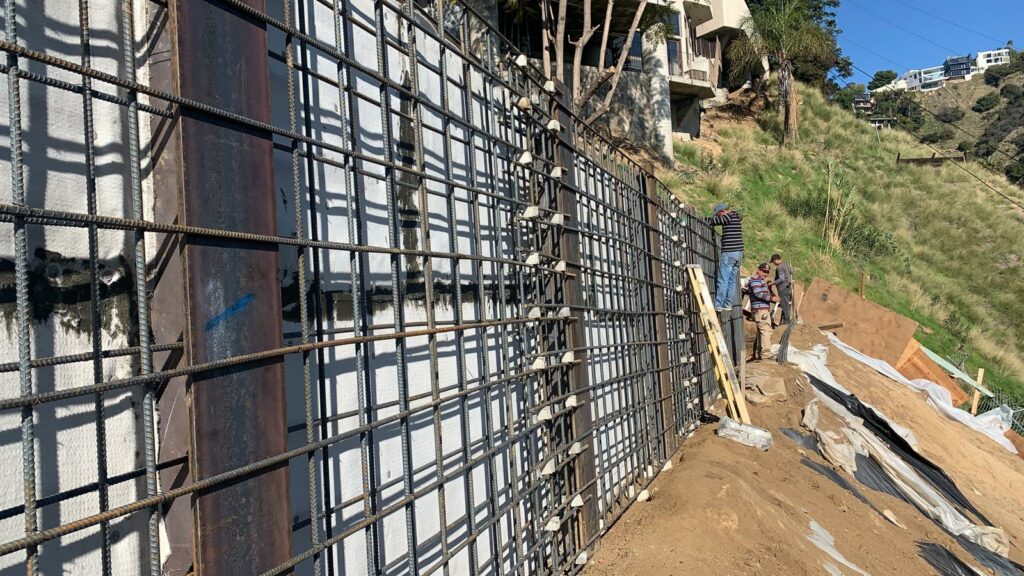 Workers installing rebar for retaining wall construction.