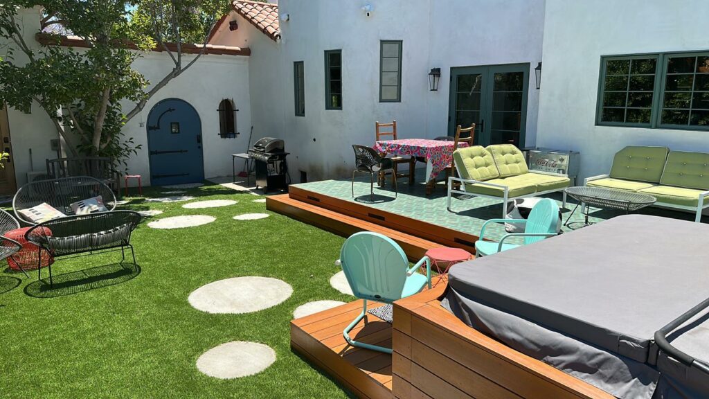 Sunny backyard patio with outdoor furniture and artificial grass.