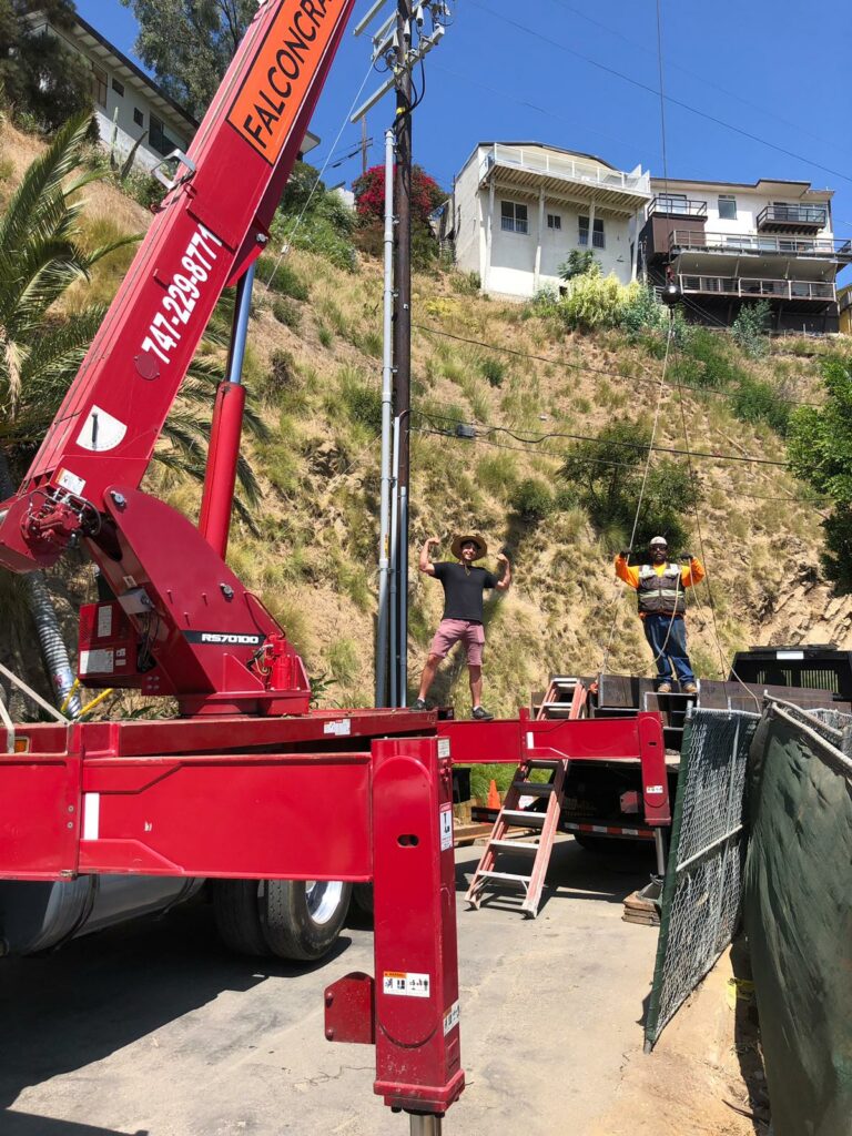 Construction workers using crane for hillside project.