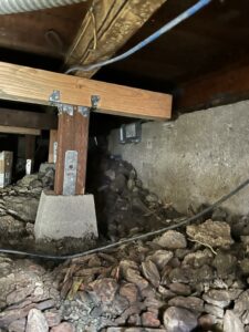 Crawlspace with wooden support beams and concrete pier.