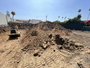 Excavator at construction site with piles of dirt.