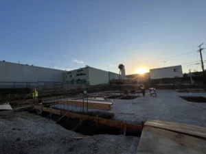 Construction site at sunset with workers.