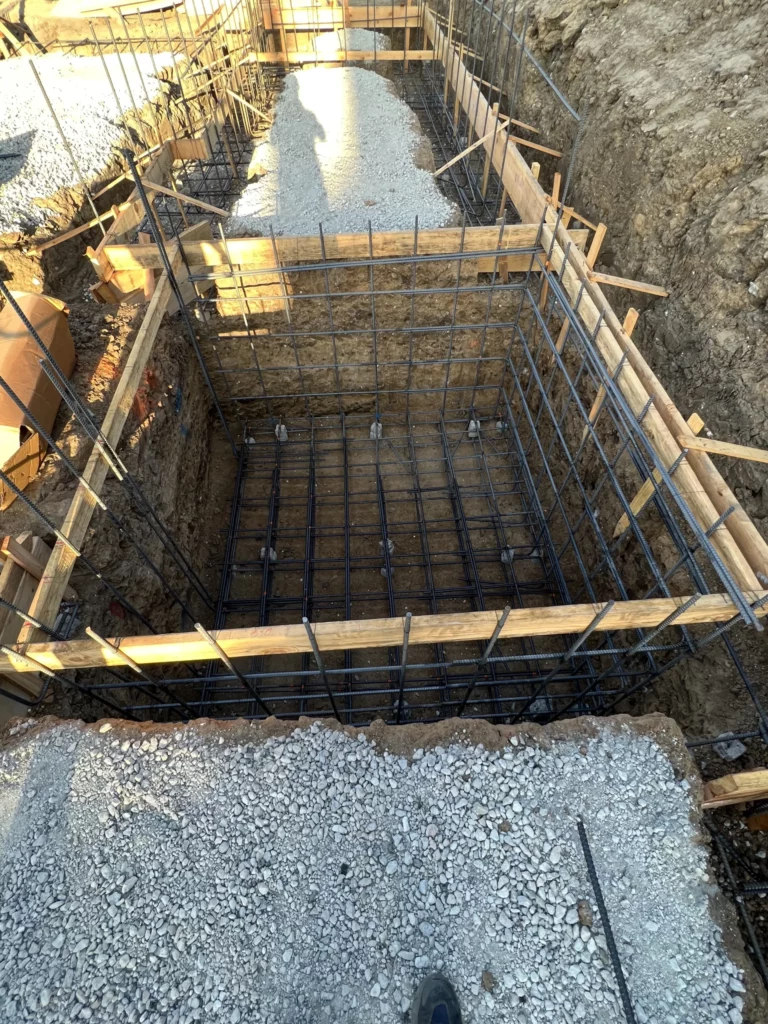 Construction foundation with rebar and wooden formwork.