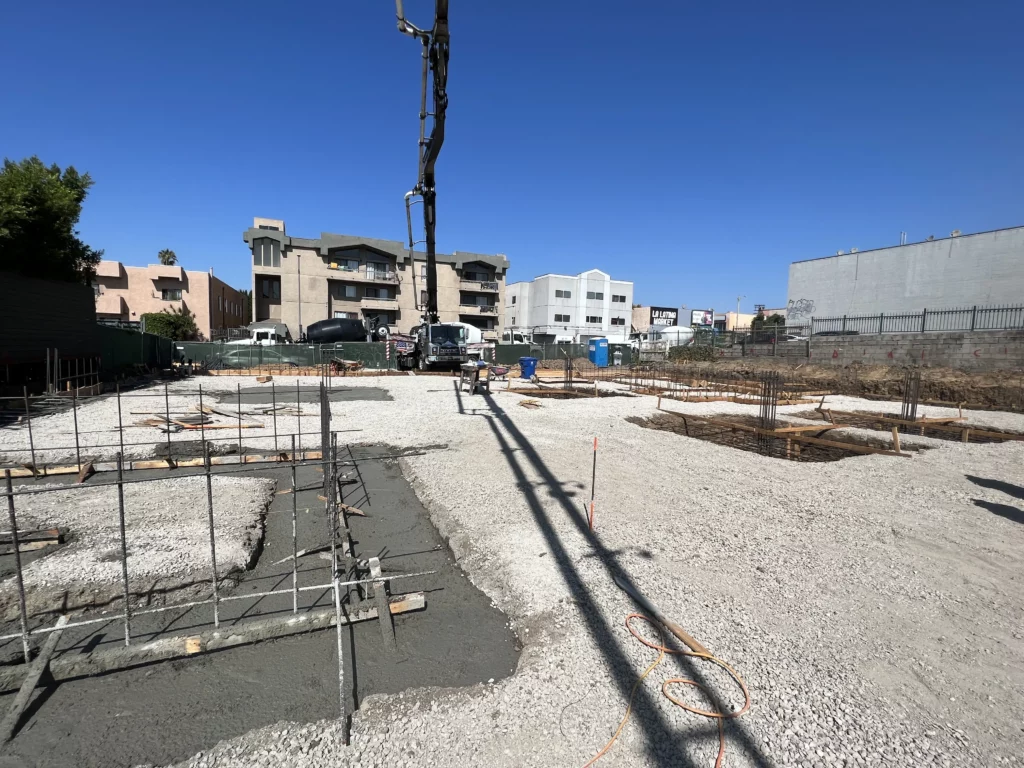 Construction site with concrete foundations and clear sky.