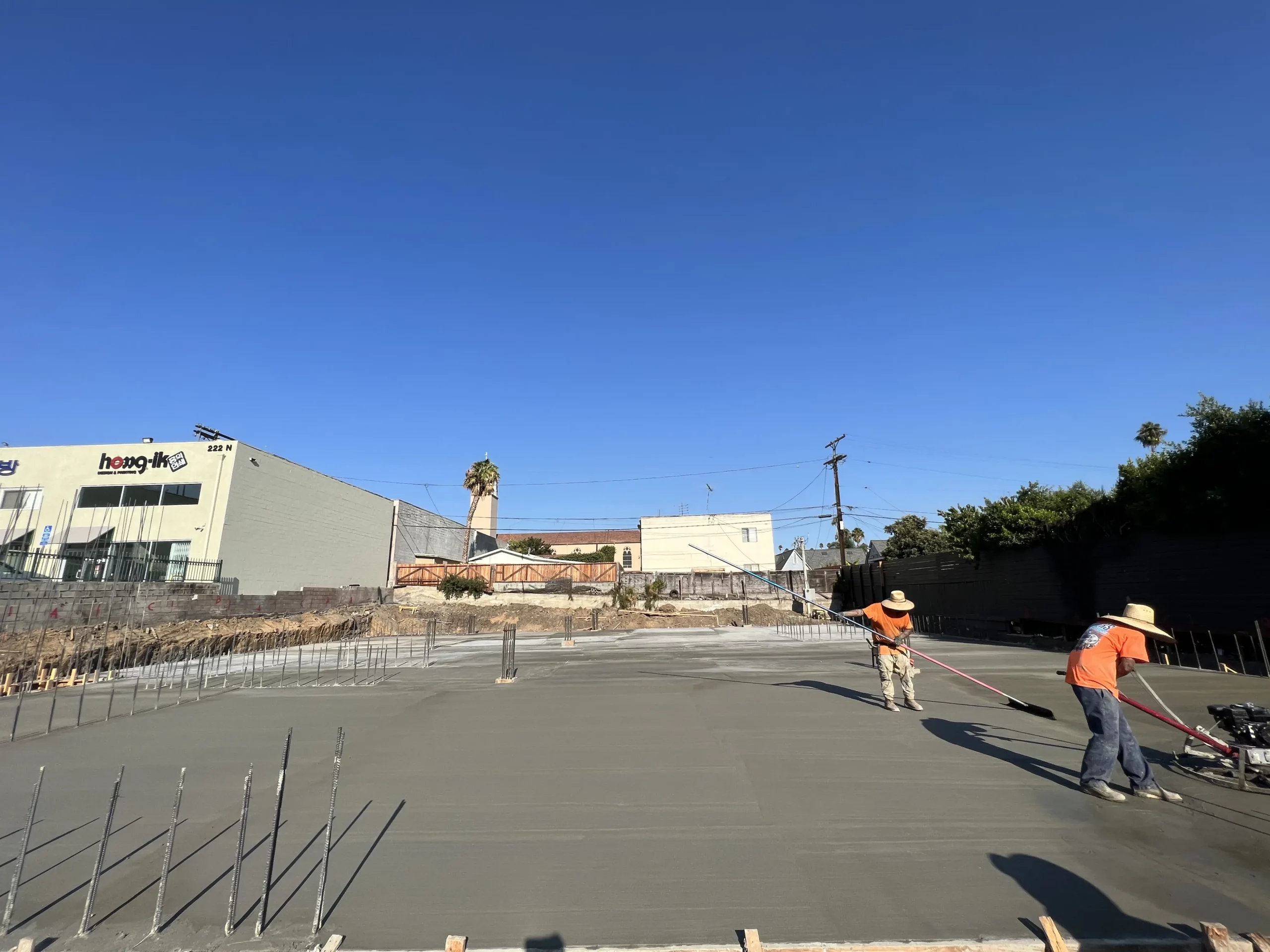 Workers smoothing concrete at construction site.