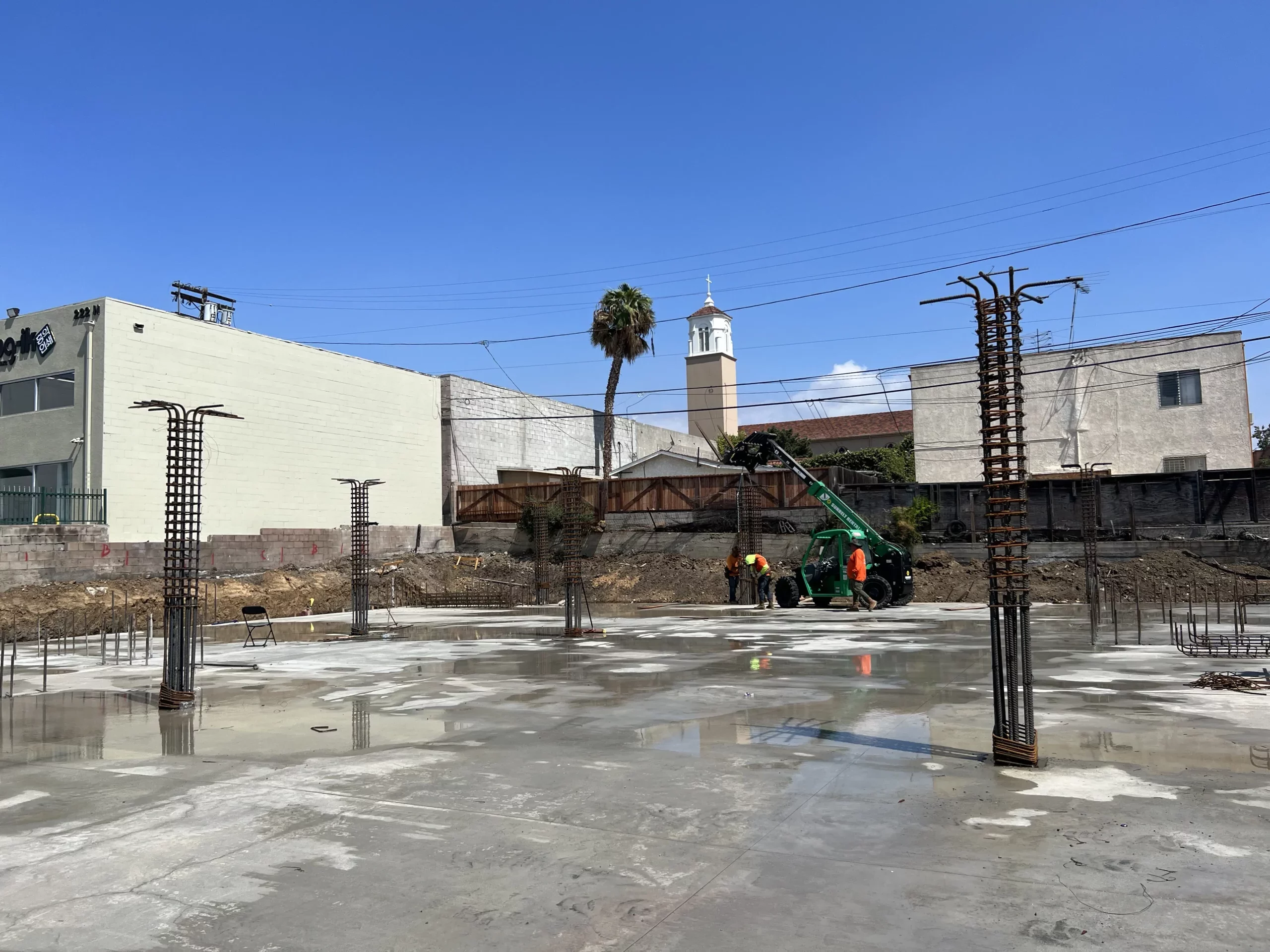 Construction site with workers, machinery, and steel rebar.