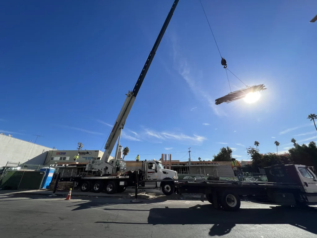 Mobile crane lifting materials at construction site.