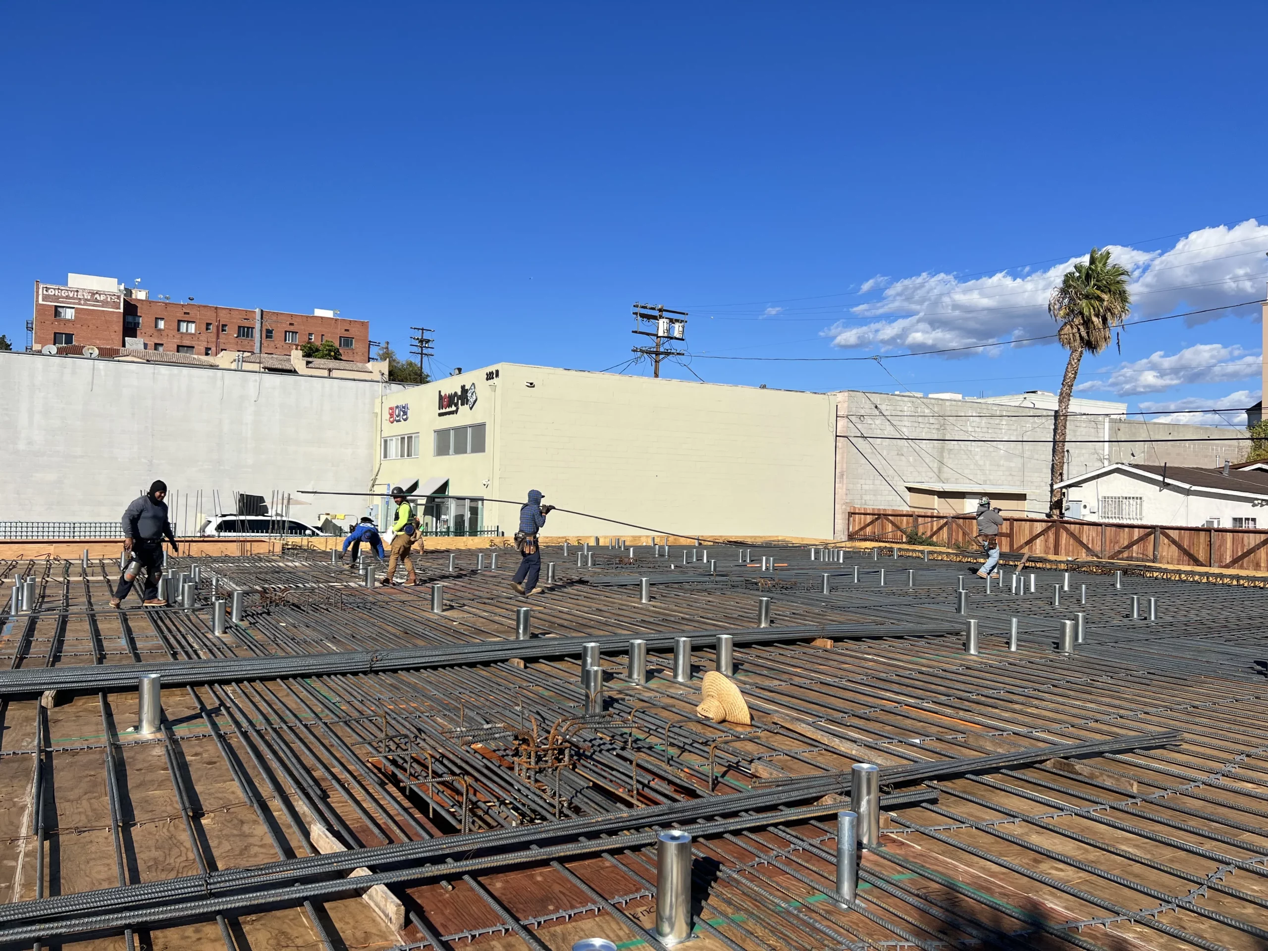 Construction workers laying rebar at building site.
