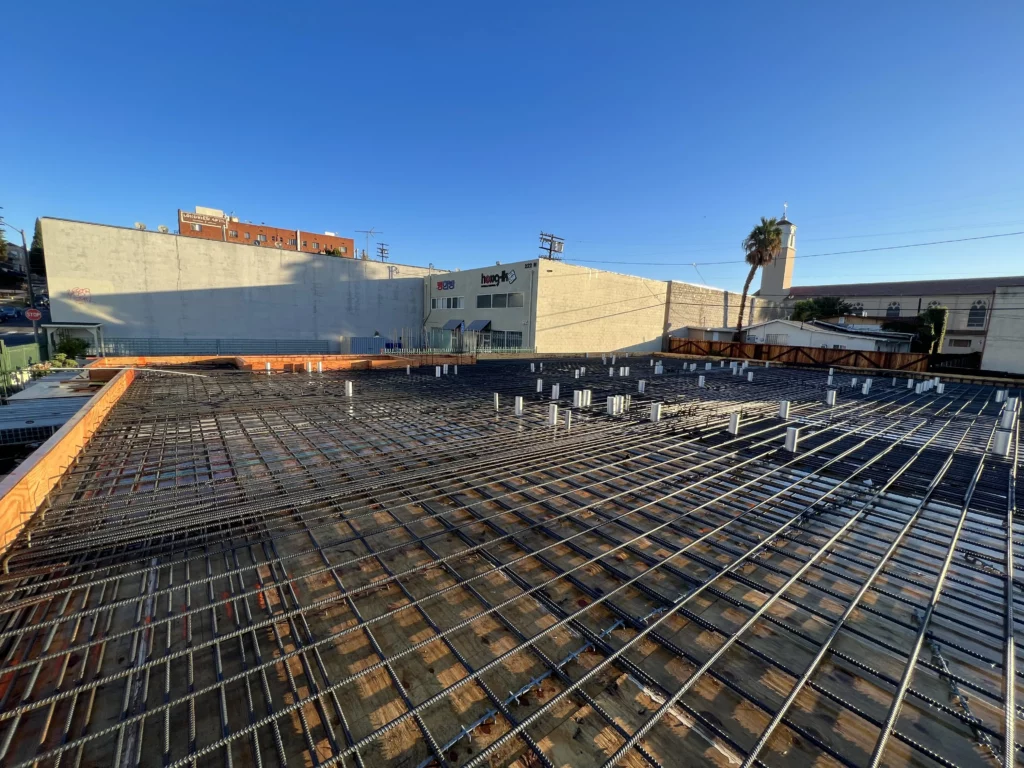Urban construction site with rebar framework and clear sky.