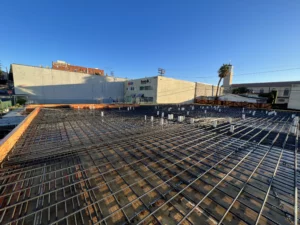 Construction site with steel rebar framework, urban backdrop.