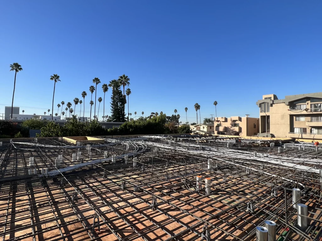 Construction site with rebar framework and palm trees