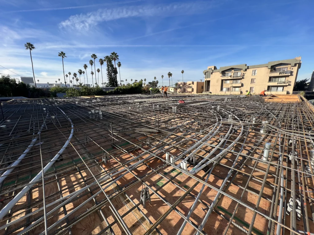 Construction site with rebar framework and palm trees.