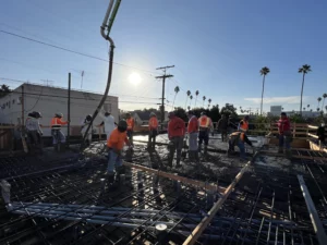 Construction workers pouring concrete at building site.