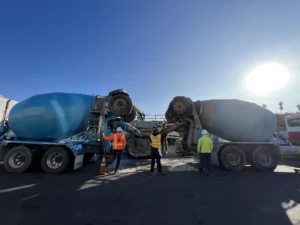 Workers inspecting overturned cement truck.