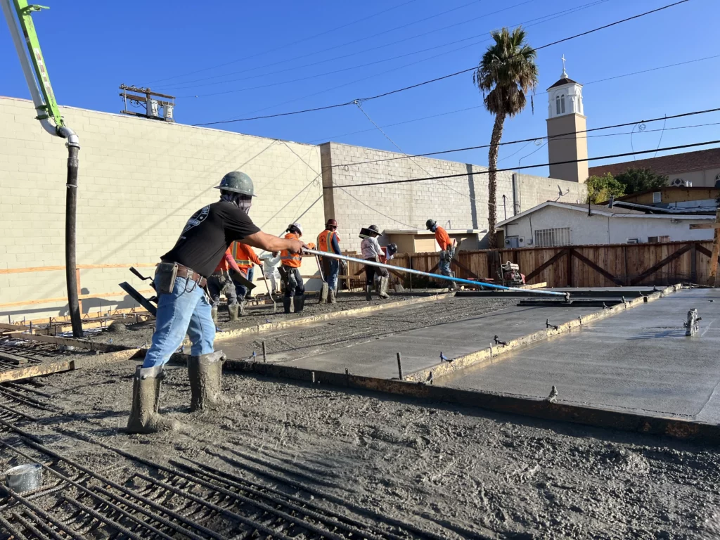 Construction workers pouring concrete at a work site.