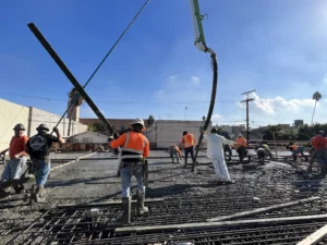 Construction workers pouring concrete with pump.
