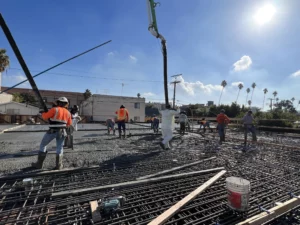 Construction workers pouring concrete at building site.