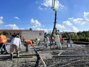 Construction workers pouring concrete at building site.