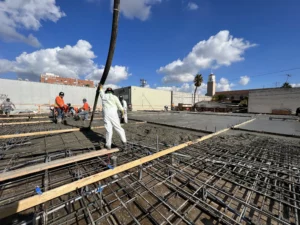 Workers pouring concrete foundation at construction site.