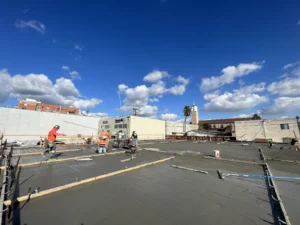 Construction workers pouring concrete on a sunny day.