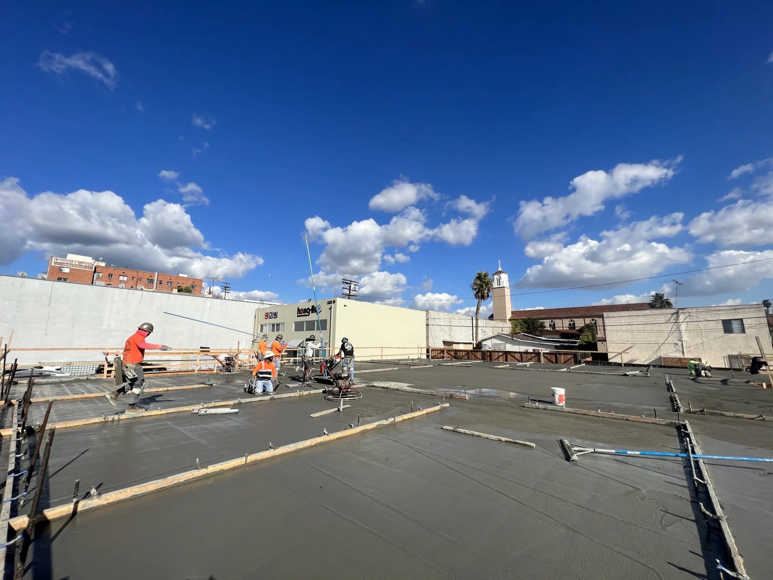 Construction workers pouring concrete on a sunny day.