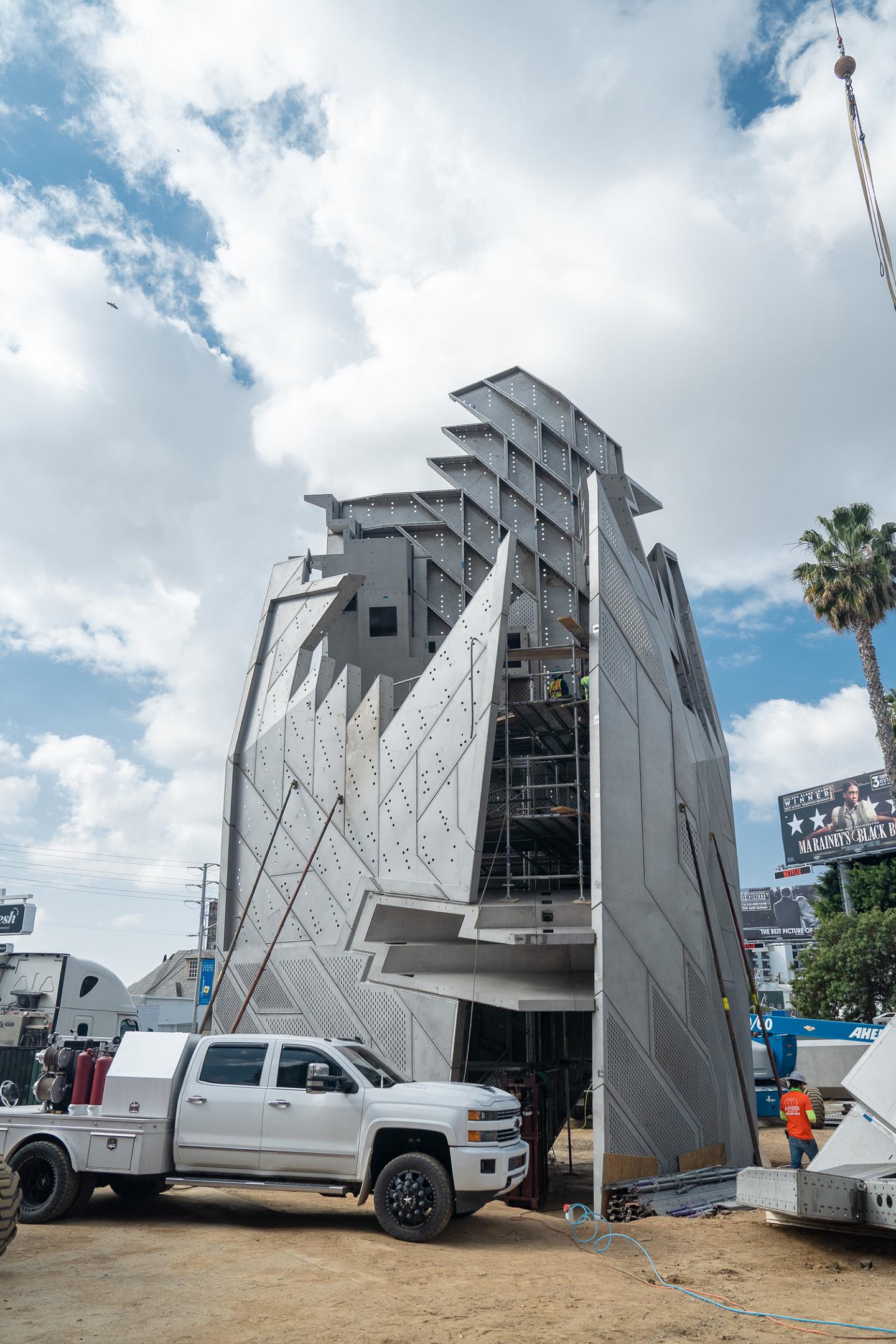 Modern building under construction with crane and truck.