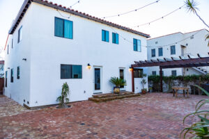 White stucco house with brick patio and pergola.