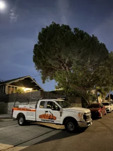 Construction truck parked at night under moonlit sky.